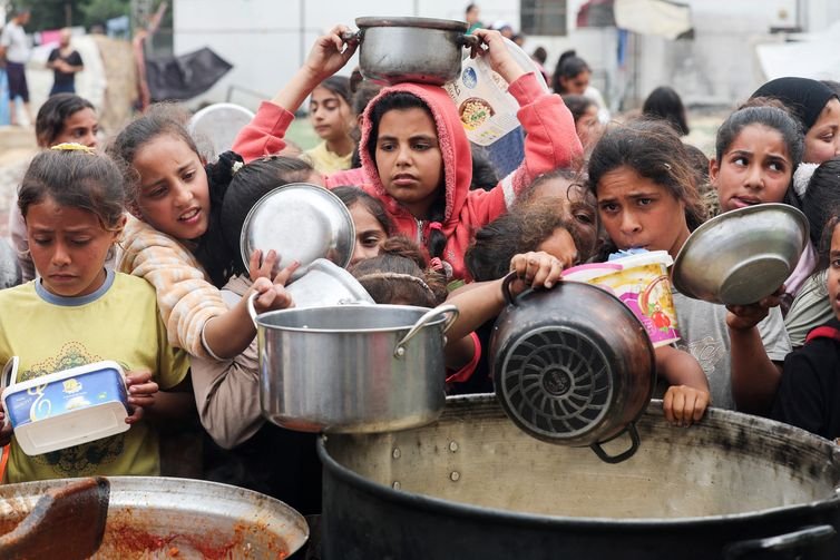 Palestinos aguardam para receber comida preparada por uma cozinha comunitária, em Nuseirat, Faixa de Gaza 08/04/2025 REUTERS/Ramadan Abed