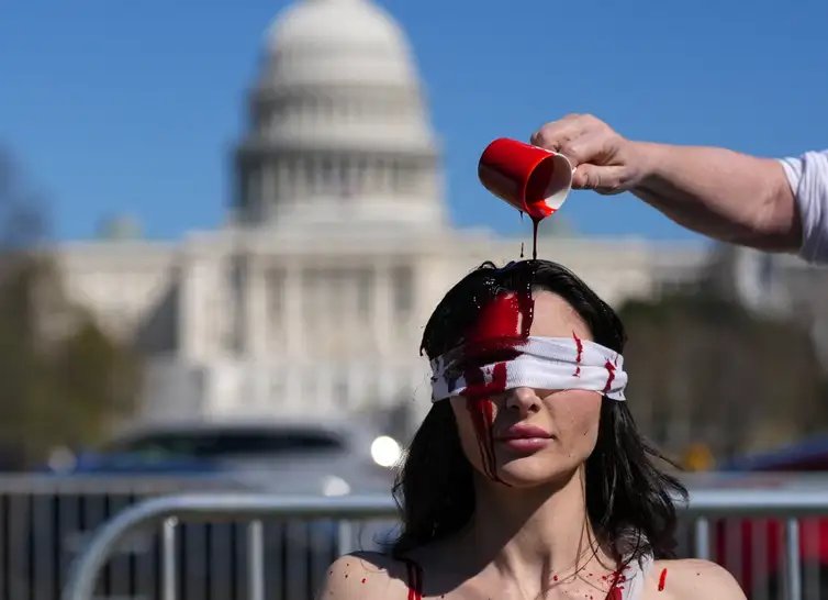 Lreuters/EAH MILLIS//Proibida reprodução Demonstrator Sam Scarcello, in costume, has fake blood poured on her head during a