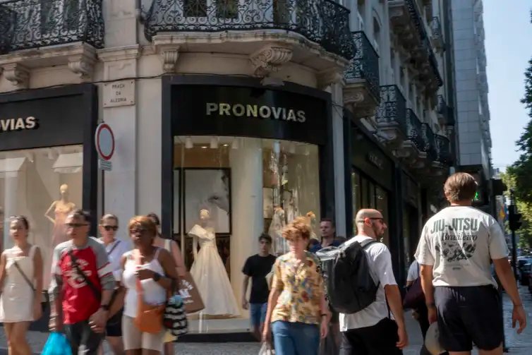 In Lisbon, Portugal, on August 2, 2025, people walk past a Pronovias storefront. The Spanish bridalwear company reports EUR135.9 million in revenue for 2023 and a net loss of EUR128.6 million. In early 2025, Pronovias reduces its capital by EUR193 million and appoints Cristina Alba Ochoa as CEO to lead a new turnaround strategy focused on international growth and financial stabilization by 2027. (Photo by Luis Boza/NurPhoto)NO USE FRANCE