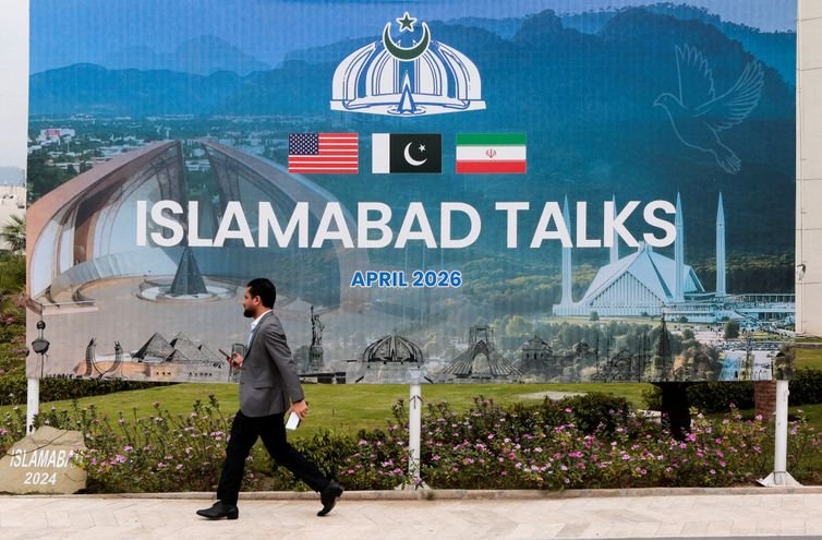 A man walks past a billboard near the media centre as delegations from the United States and Iran are expected to hold peace talks in Islamabad, Pakistan, April 11, 2026. REUTERS/Asim Hafeez TPX IMAGES OF THE DAY REFILE - CHANGING FROM 